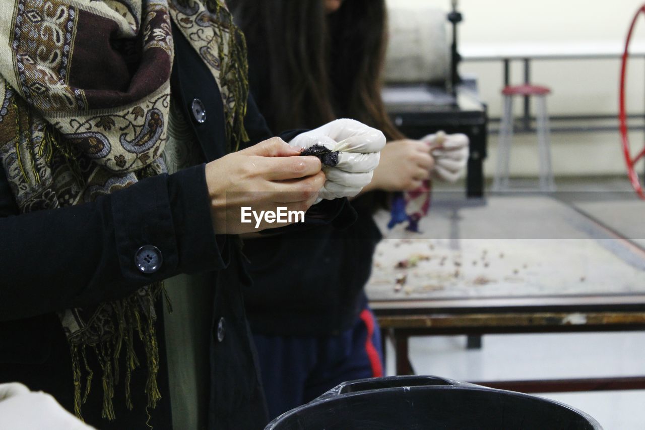 Midsection of two women holding chemical while standing at laboratory