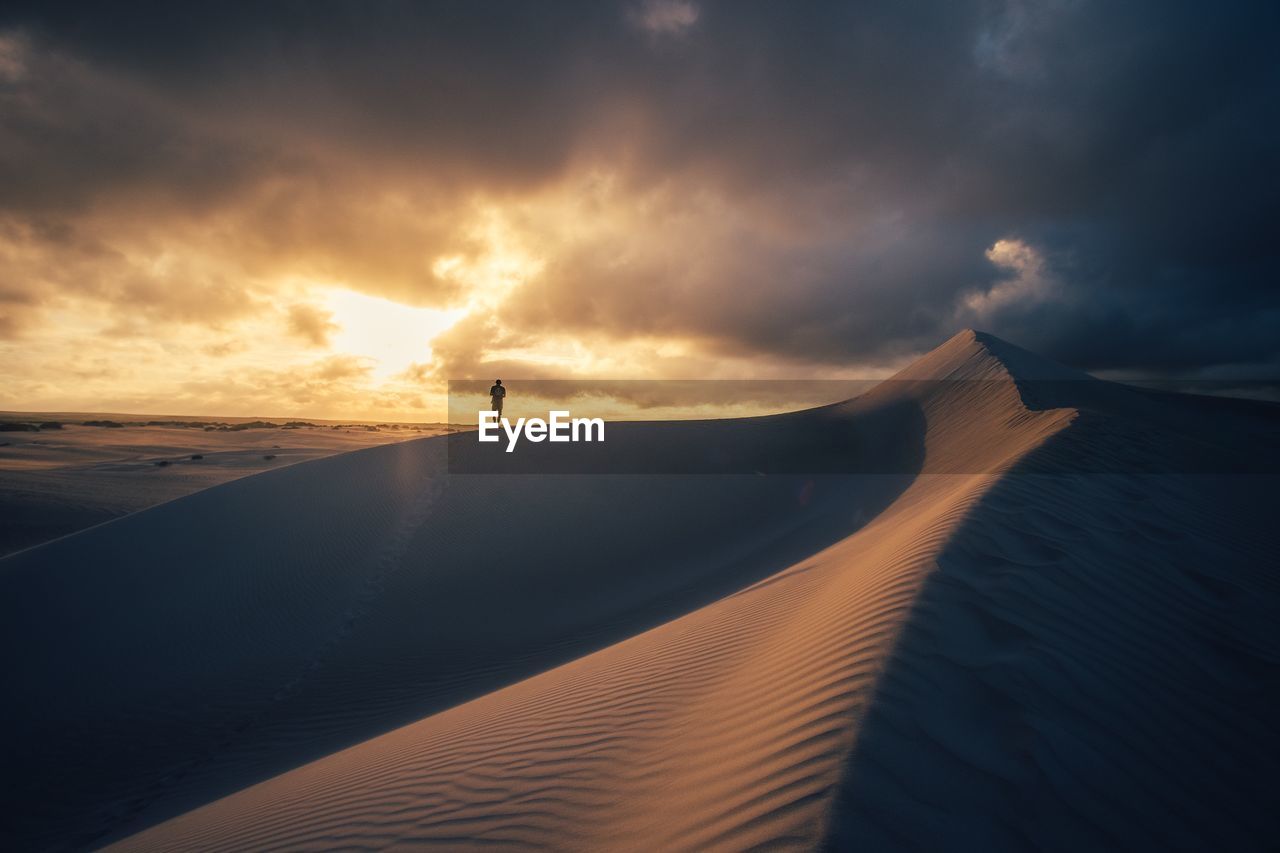 Scenic view of sand dunes against sky during sunset