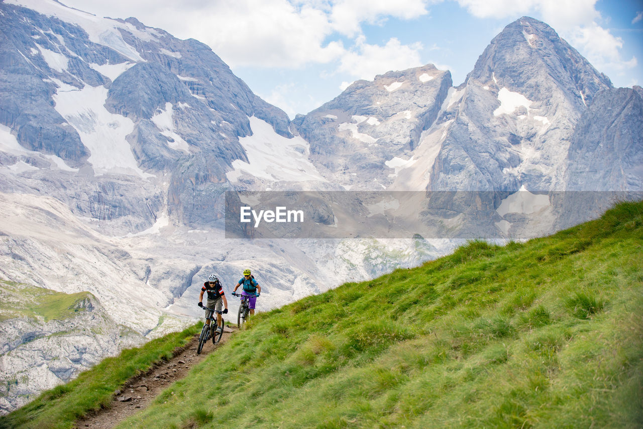 Man and woman riding their mountain bikes on footpath in the scenic dolomites, italy