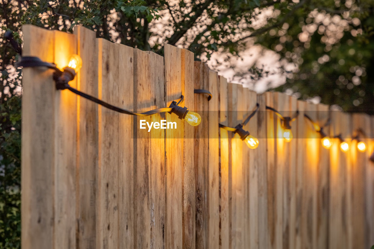 CLOSE-UP OF ILLUMINATED LAMP ON FENCE