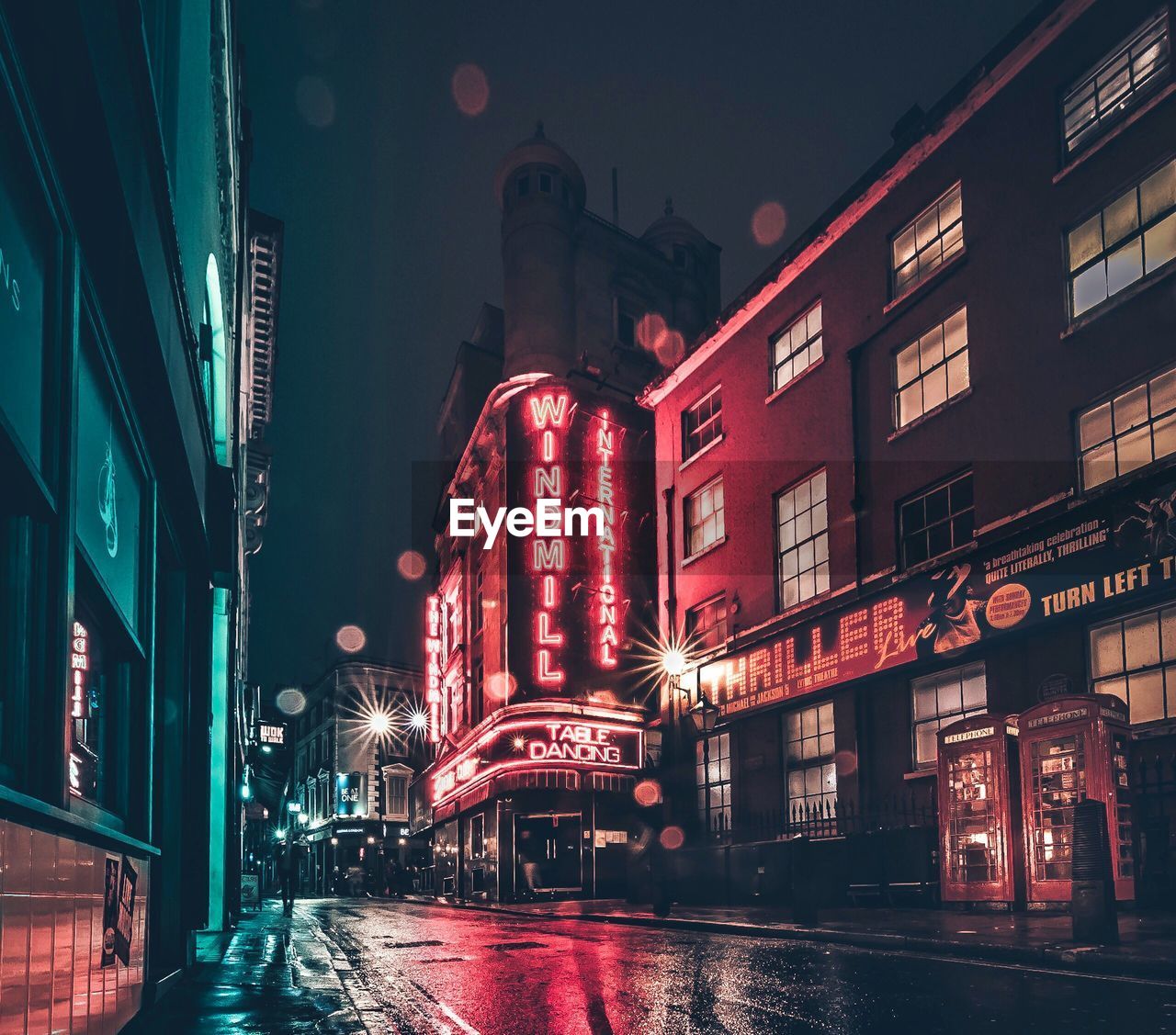 ILLUMINATED STREET AMIDST BUILDINGS AT NIGHT