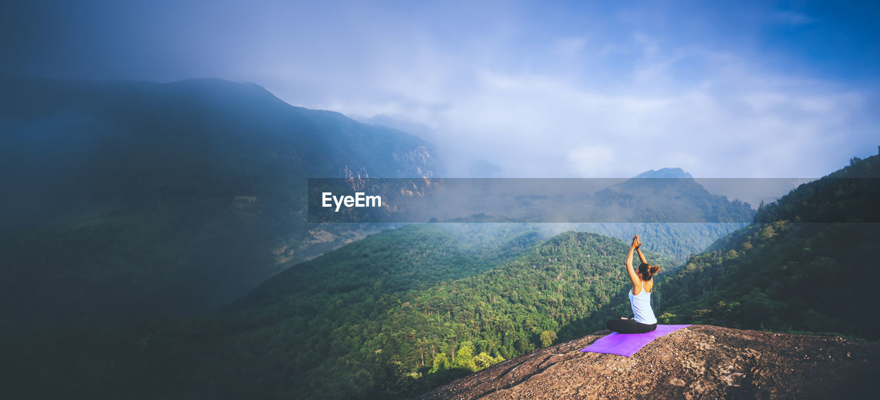 rear view of woman standing on mountain against sky