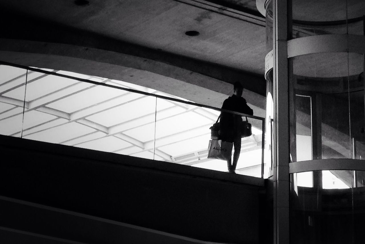 Low angle view of man standing by glass railing in shopping shop