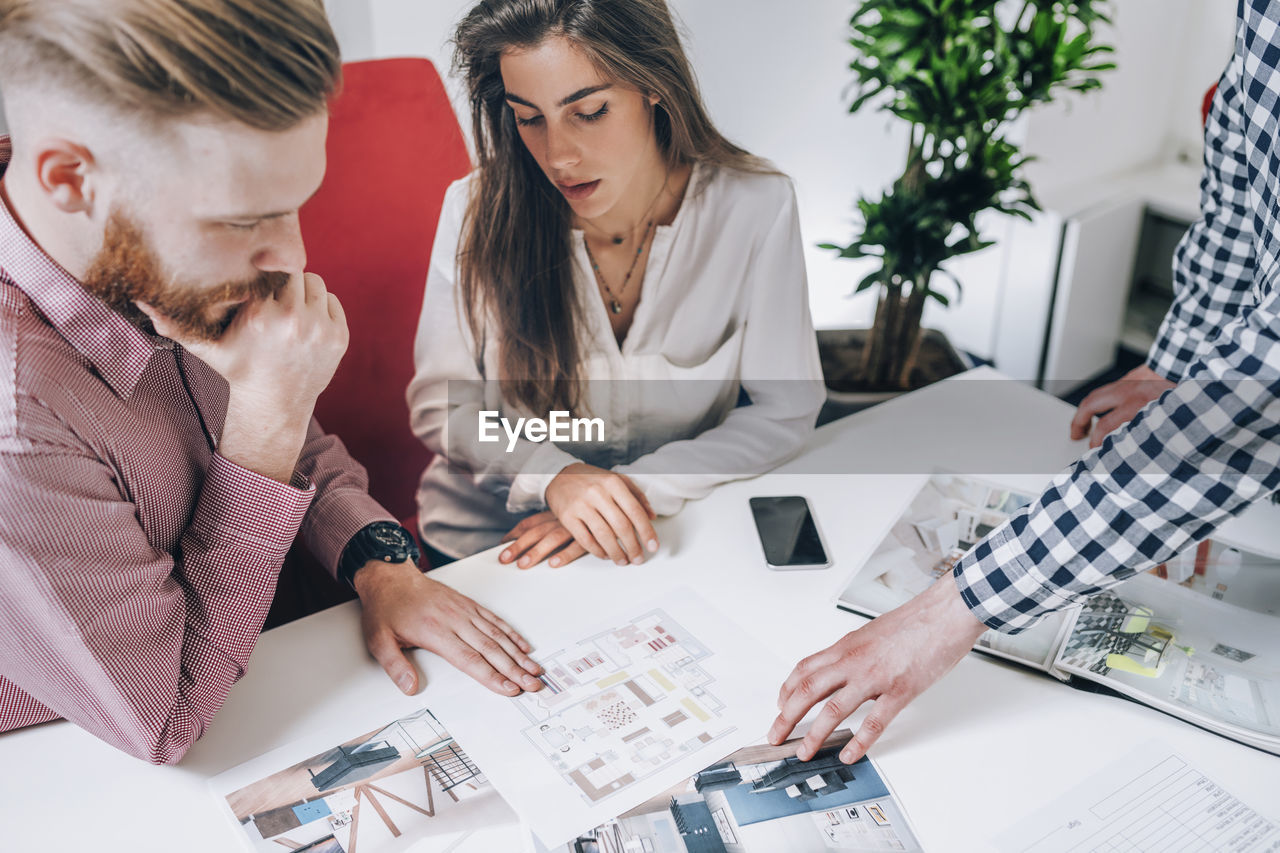 Young couple discussing over document while real estate agent explaining 