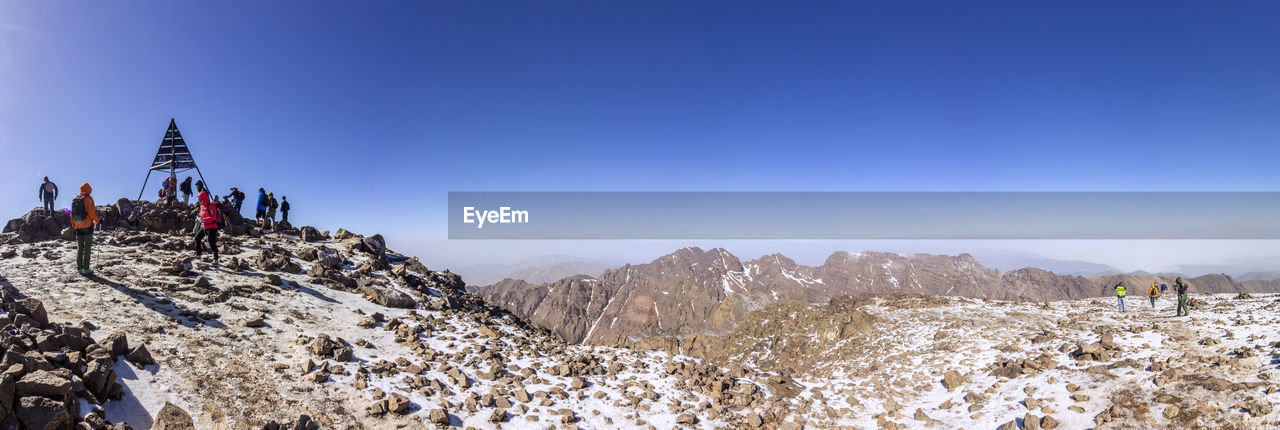 GROUP OF PEOPLE ON SNOW COVERED MOUNTAIN AGAINST SKY