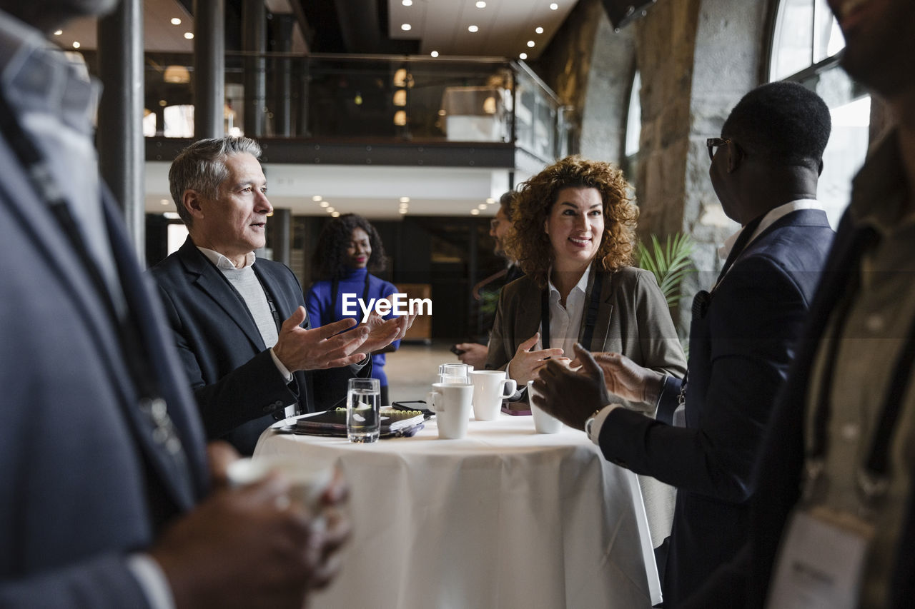 Businessmen gesturing while talking with female entrepreneur at seminar