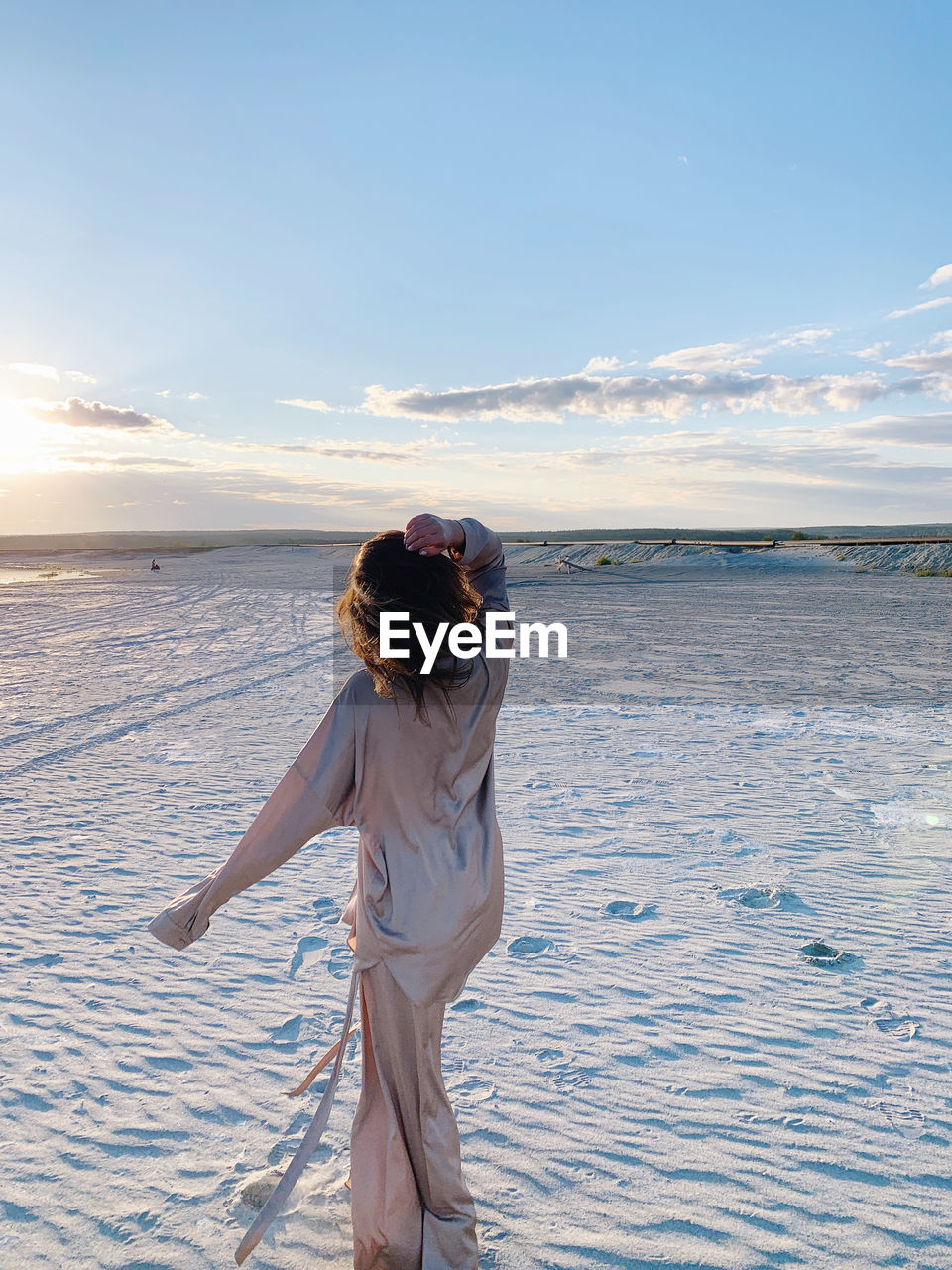 Rear view of woman standing on beach against sky