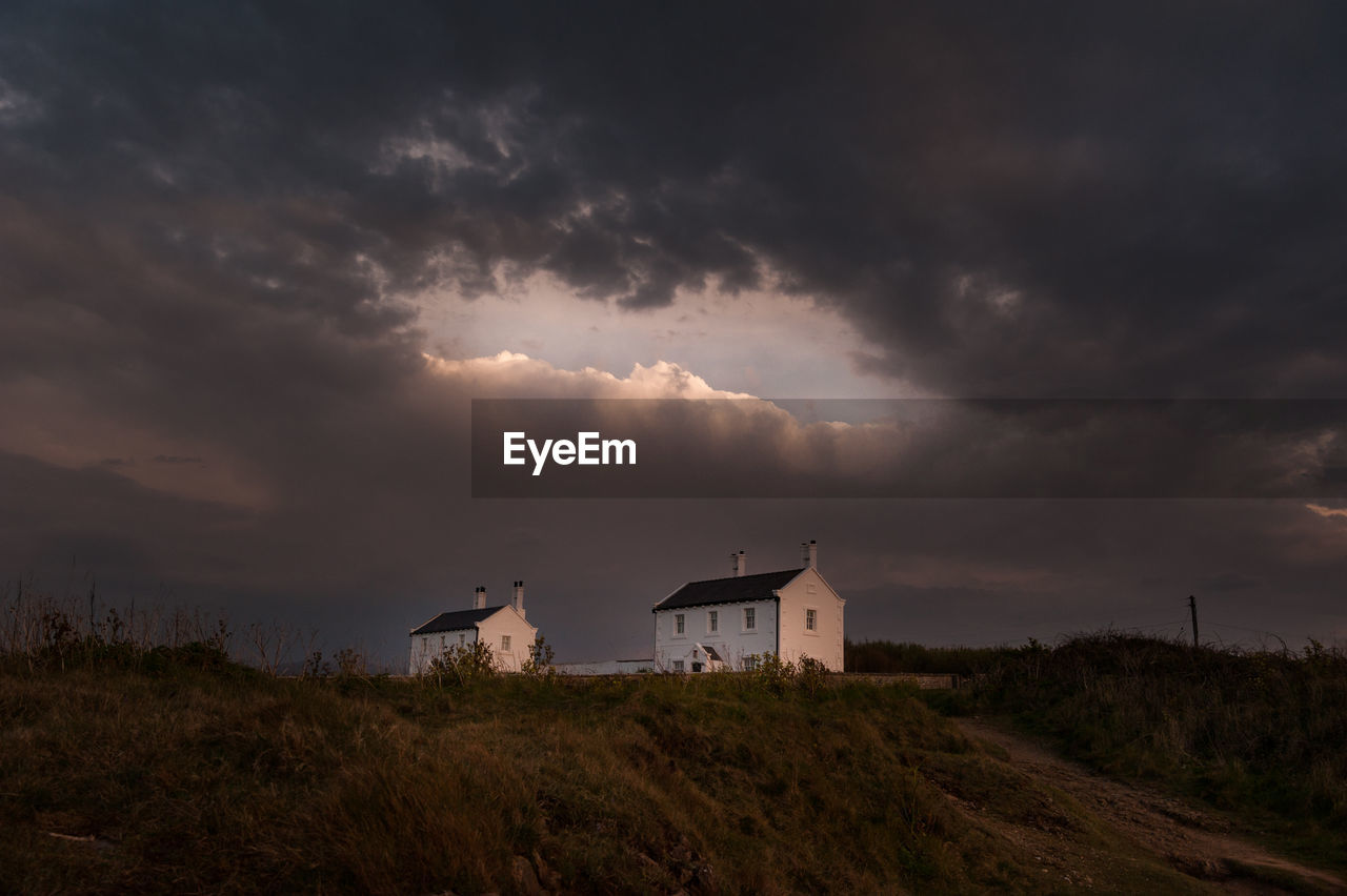 HOUSE ON FIELD AGAINST SKY AT SUNSET