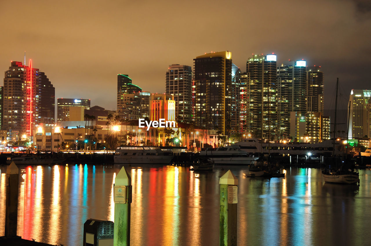 ILLUMINATED CITY BY RIVER AGAINST SKY