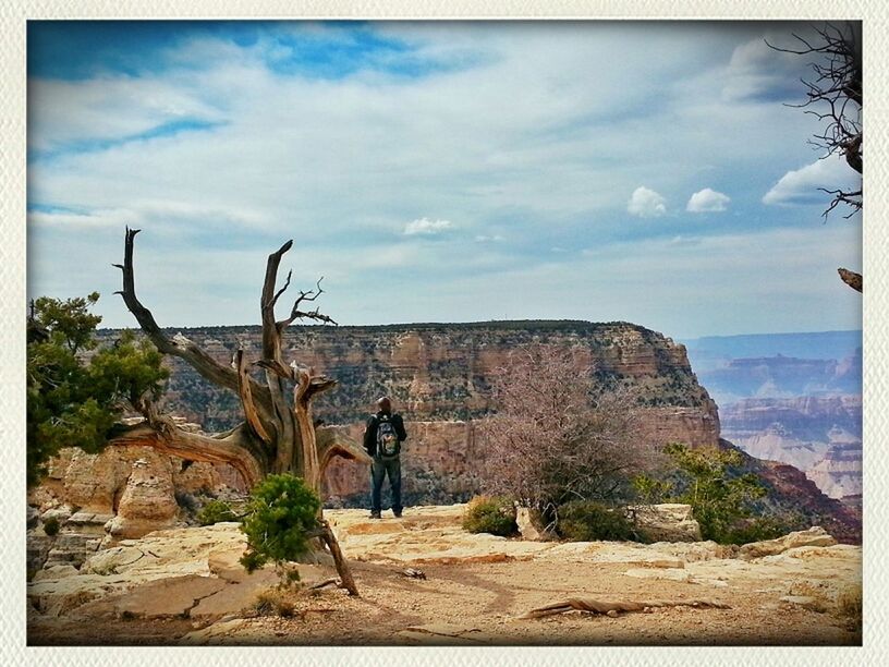 REAR VIEW OF MAN STANDING ON ROCKS