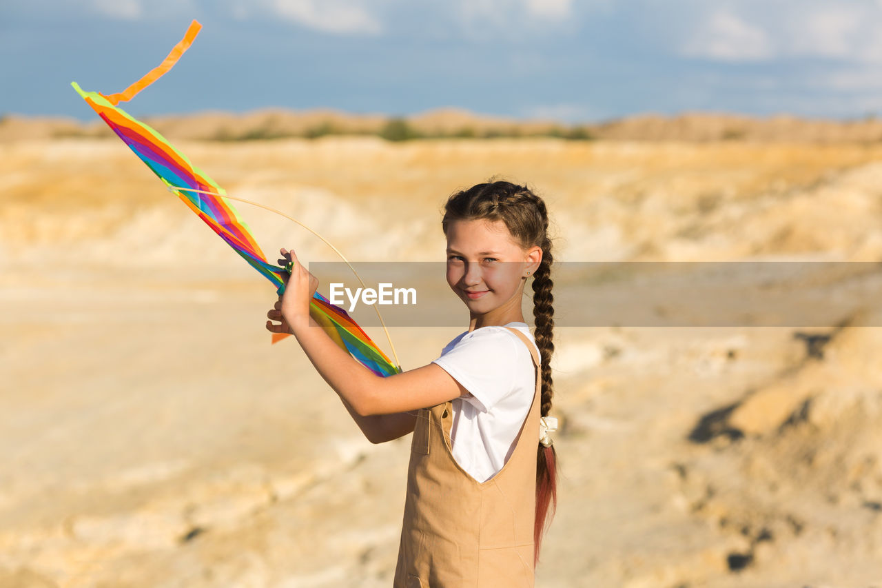 Girl with a kite in her hands on the background of mountains and desert.