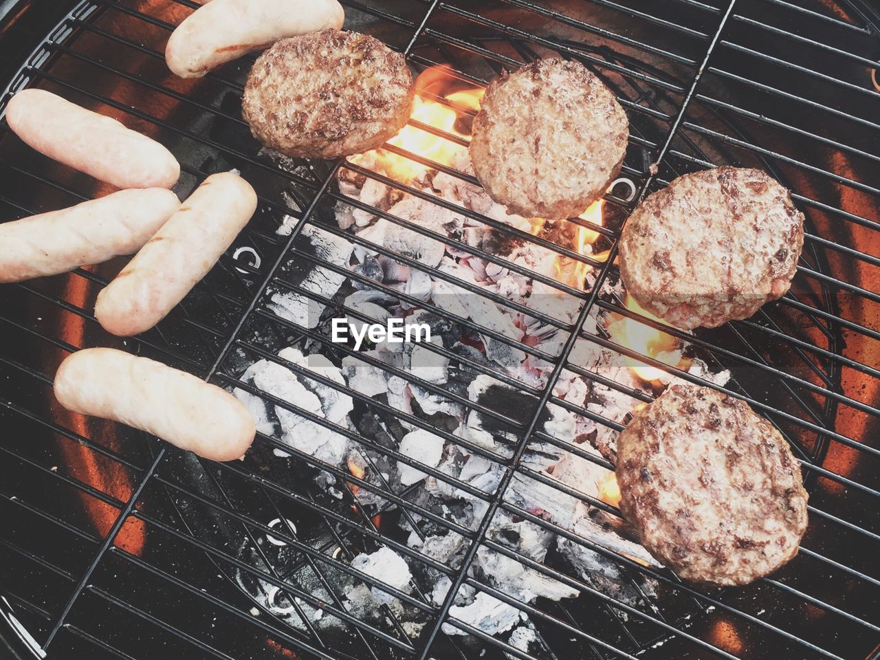 High angle view of patties and sausages on barbecue grill at yard