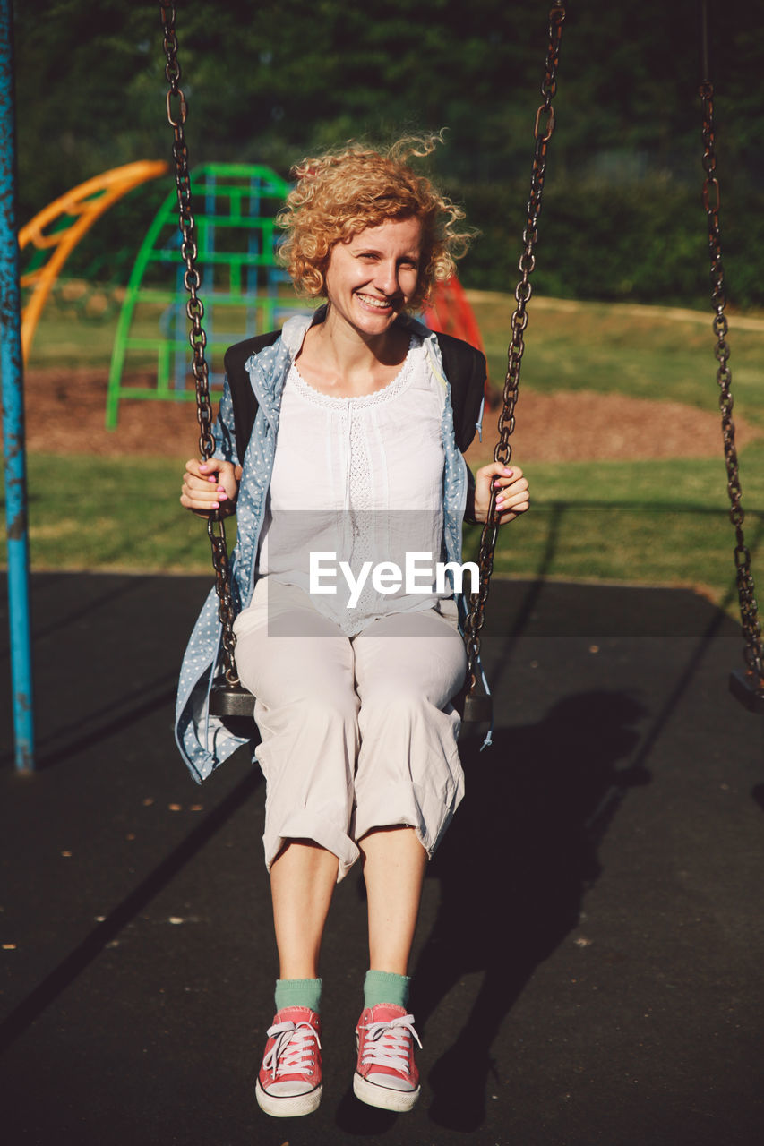 Full length of woman sitting on swing at playground