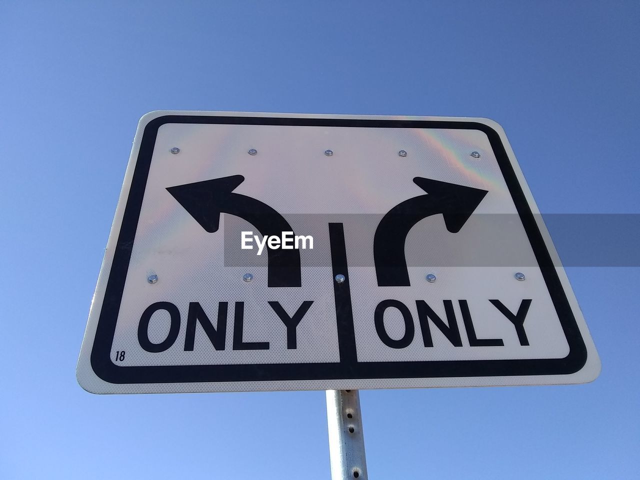 Low angle view of road sign against clear blue sky