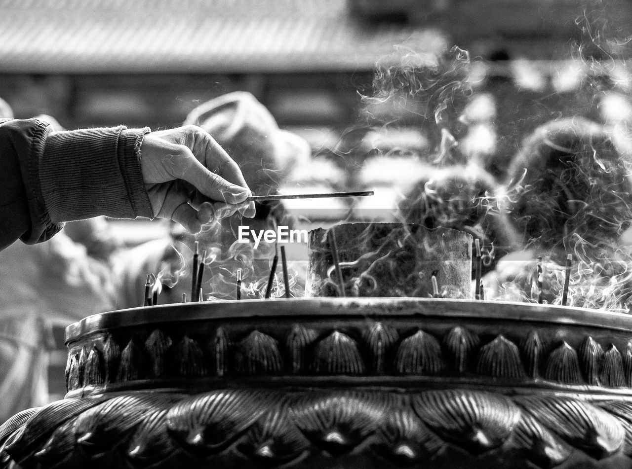 Cropped hand holding incense at temple