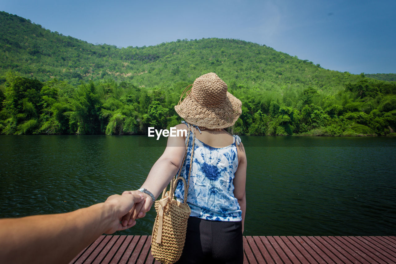 REAR VIEW OF MAN WITH WOMAN AGAINST LAKE