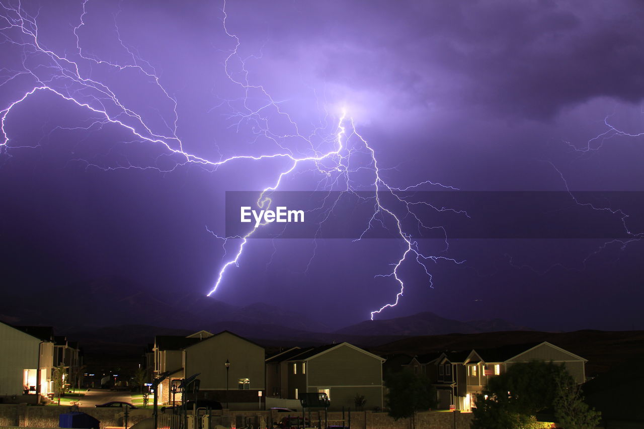 LIGHTNING OVER ILLUMINATED BUILDINGS AGAINST SKY