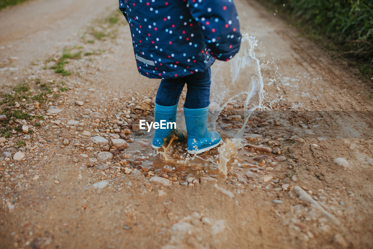 Low section of child standing on puddle