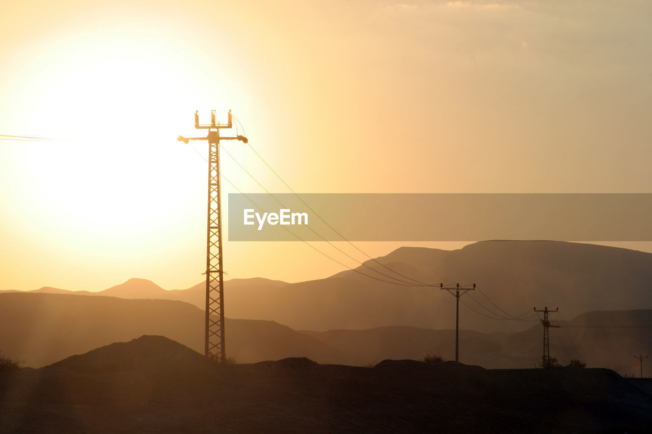 Power lines and array of electric pylons in judea desert