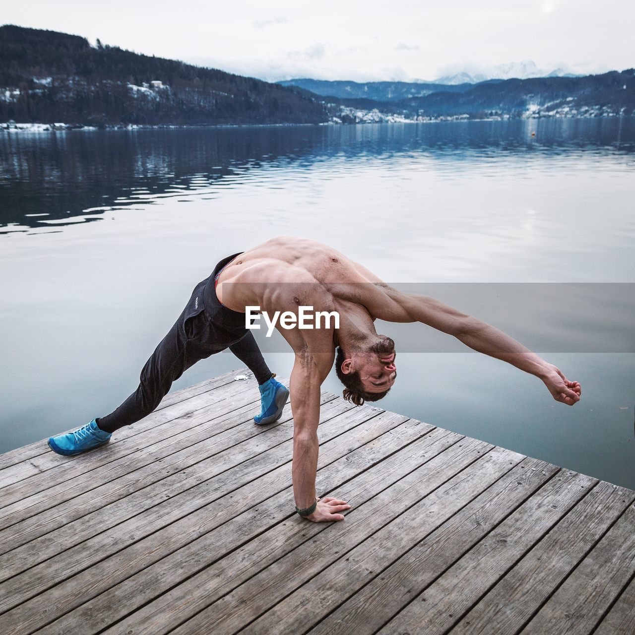 Full length of shirtless man standing on pier over lake