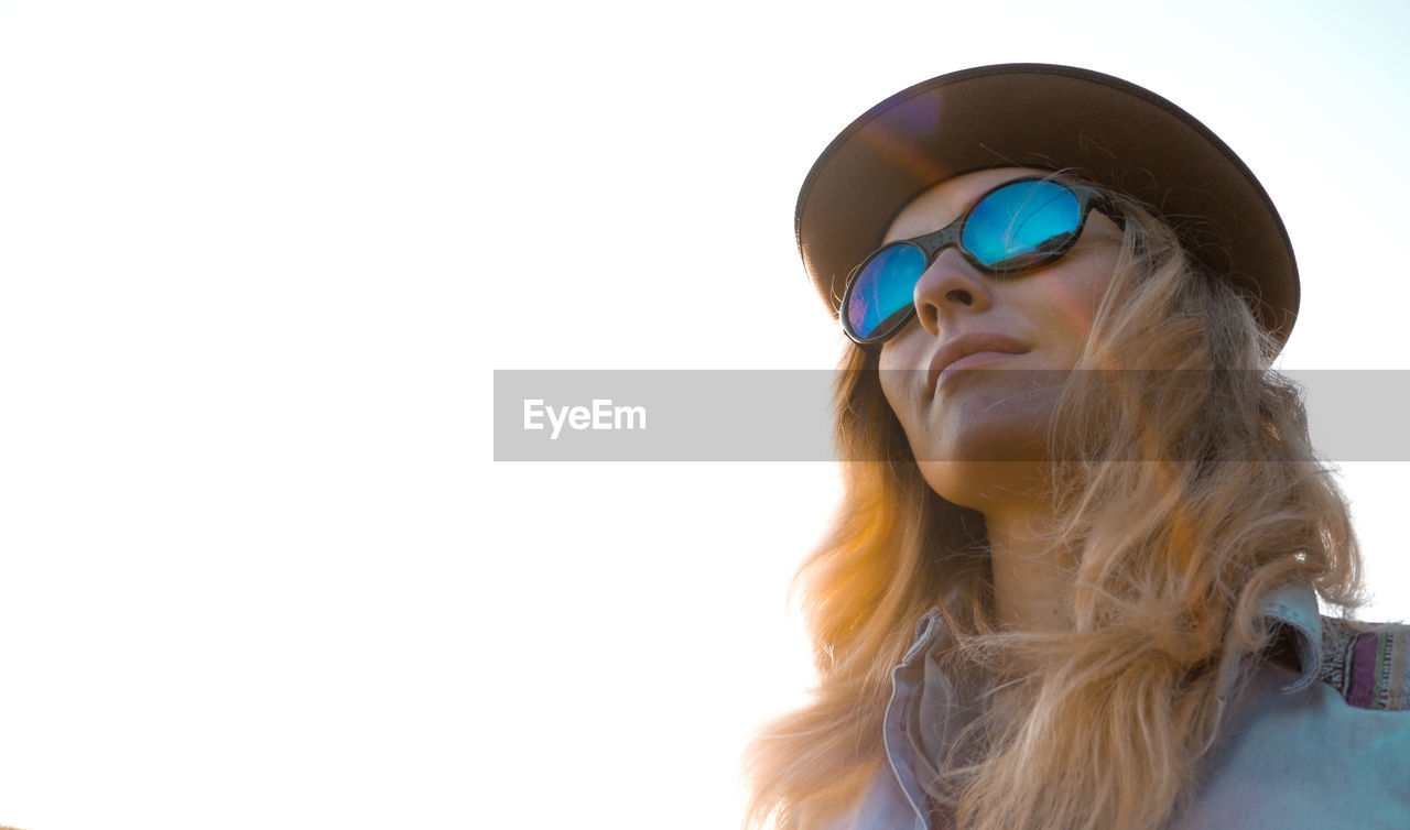 Woman in hat and sunglasses against clear sky