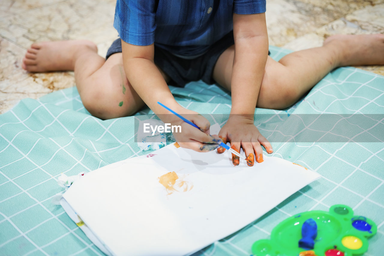 LOW SECTION OF GIRL SITTING ON PAPER