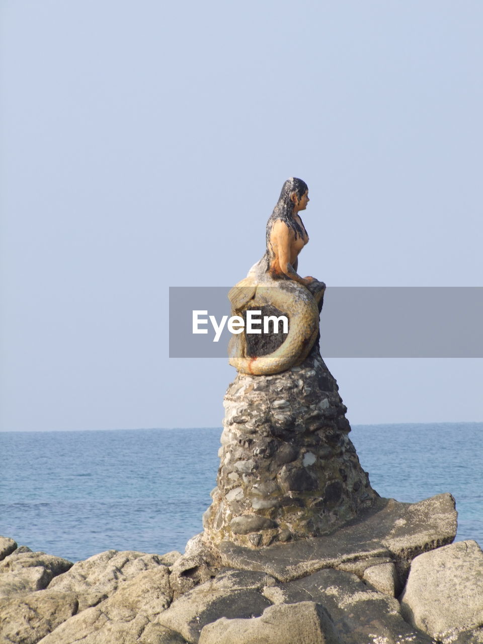 STATUE ON ROCK AGAINST SEA