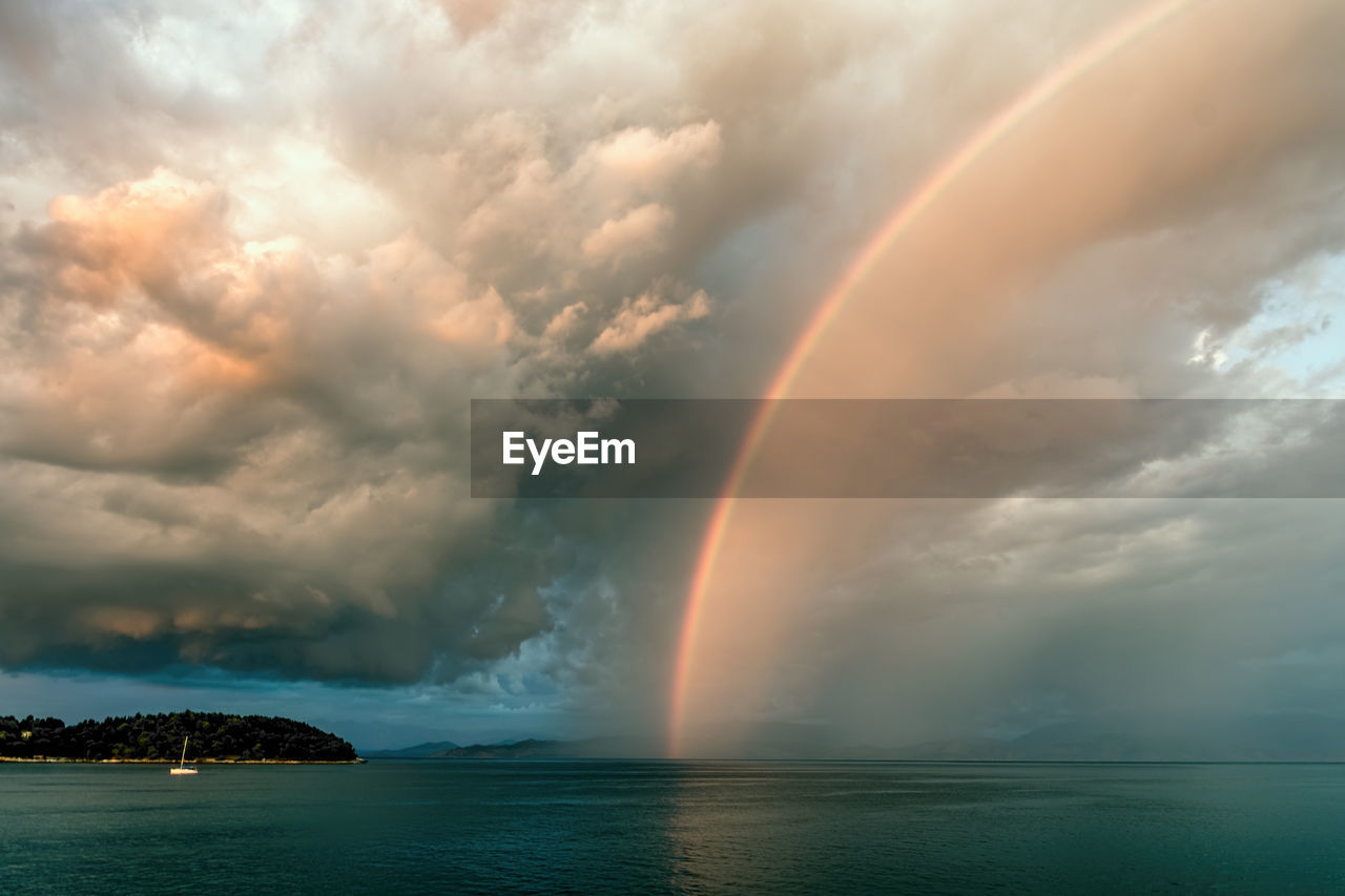 Scenic view of rainbow over sea at sunset.