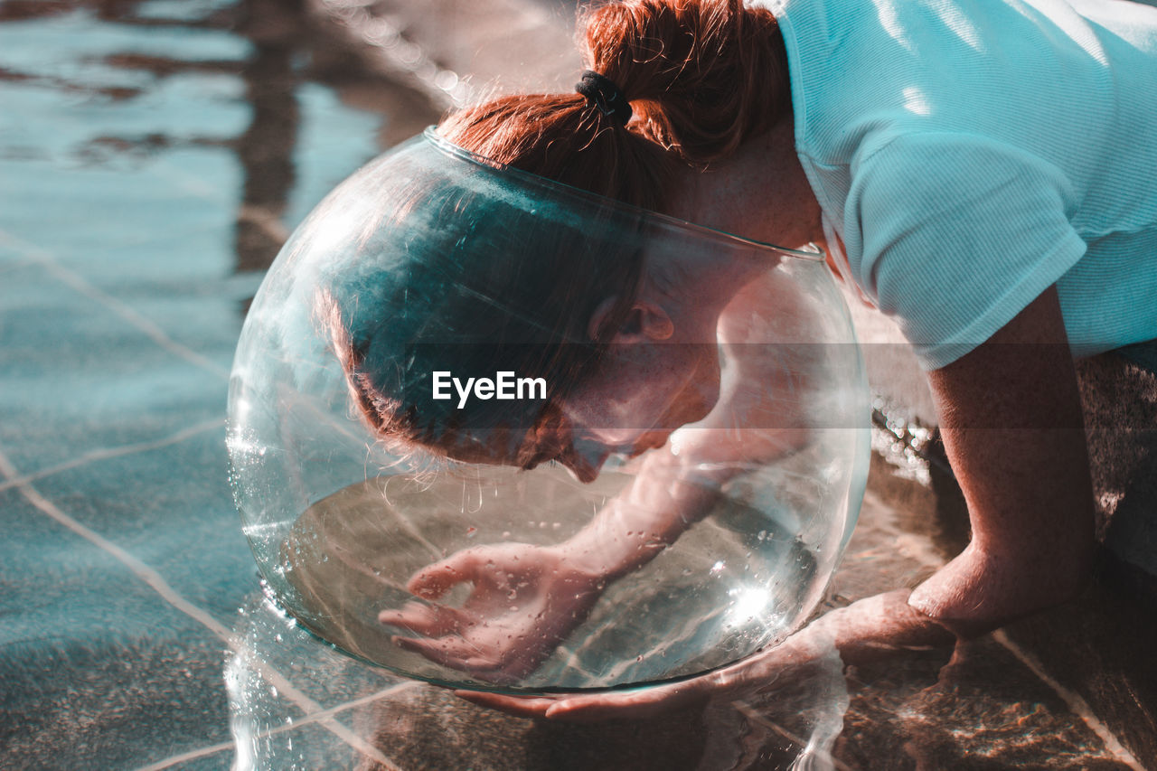 Close-up of woman wearing glass container at lake