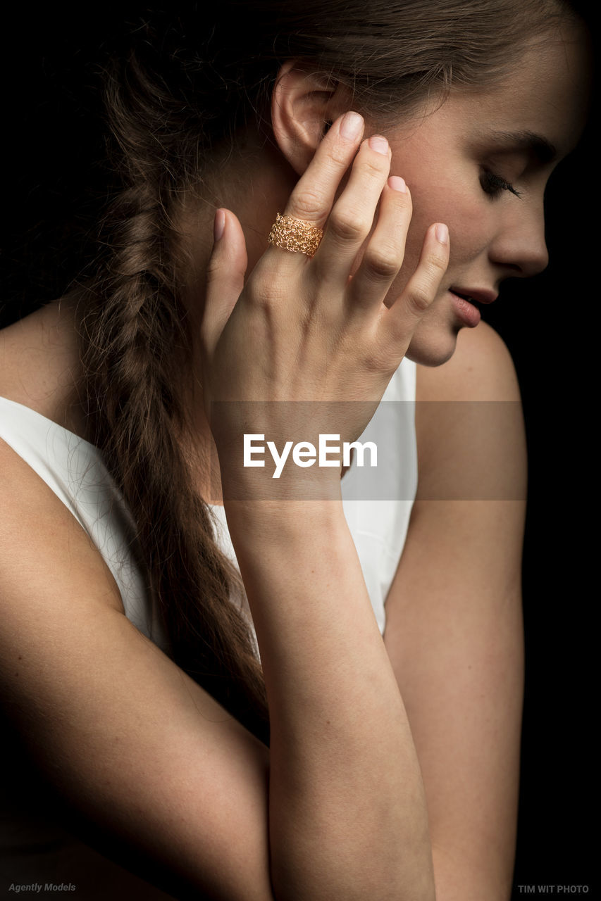 CLOSE-UP PORTRAIT OF A WOMAN COVERING FACE WITH HAND