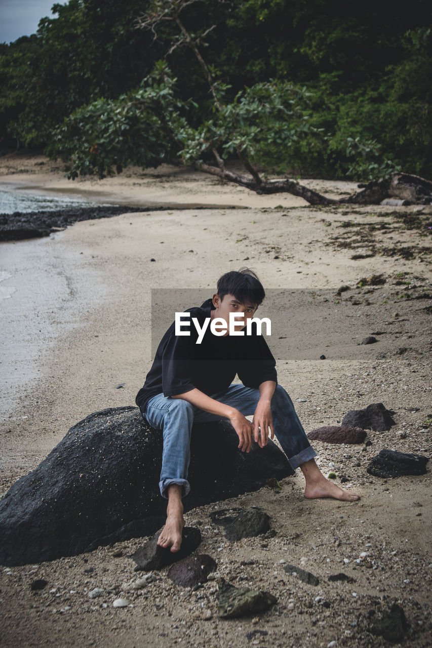 FULL LENGTH OF MAN SITTING ON ROCK