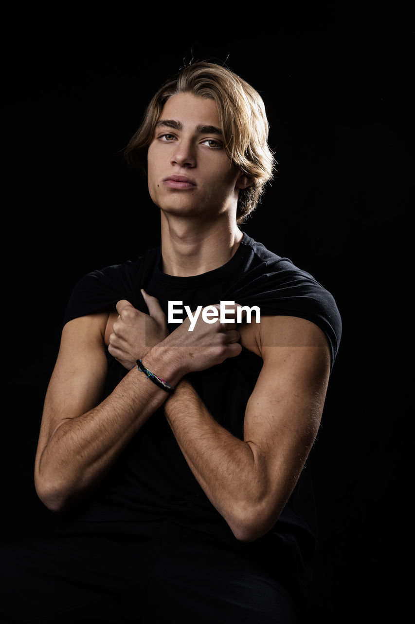 Portrait of young man against black background