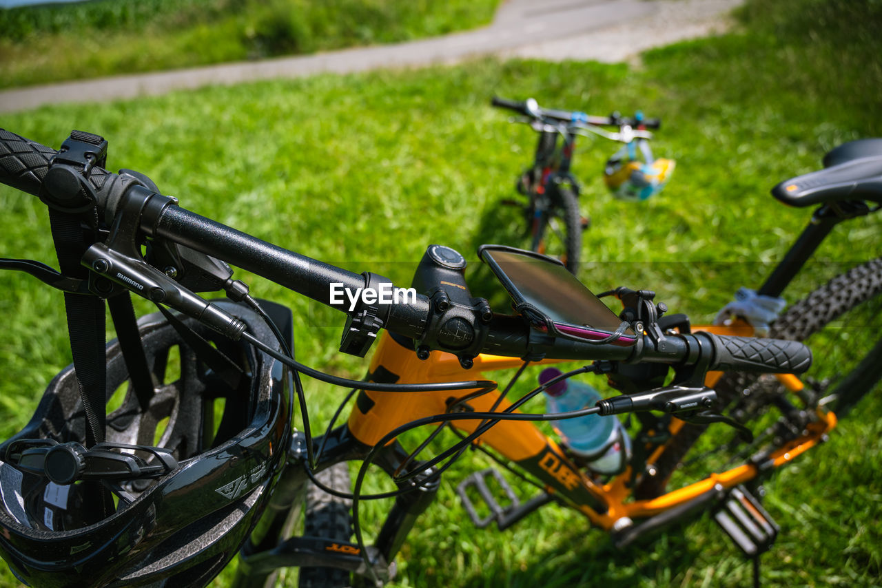 bicycle, vehicle, grass, transportation, mountain bike, land vehicle, mode of transportation, nature, road bicycle, plant, day, sports, no people, green, sports equipment, outdoors, handlebar, focus on foreground, activity, field, wheel, cycling, motorcycle