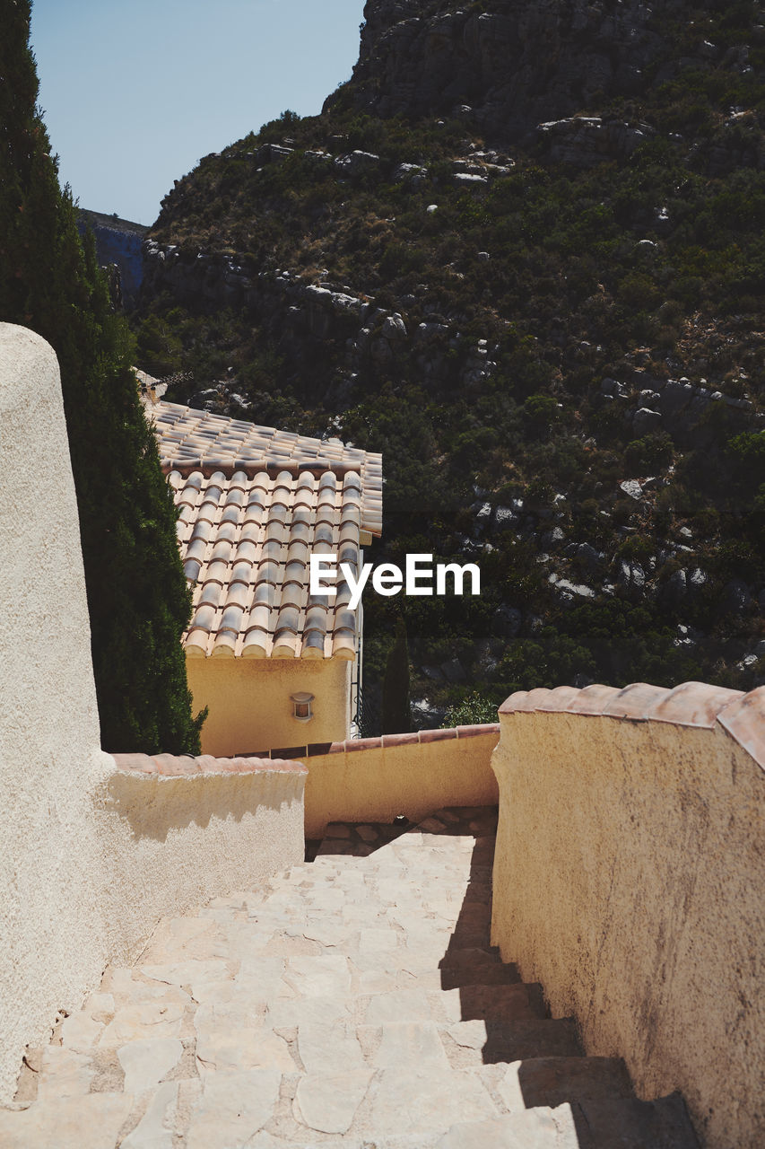 Stone wall by building against sky