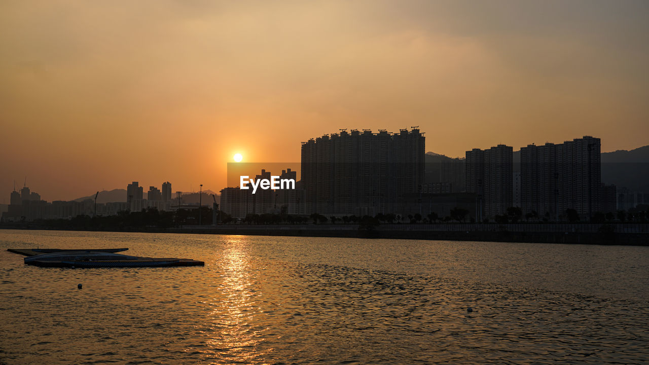 BUILDINGS BY SEA AGAINST SKY DURING SUNSET
