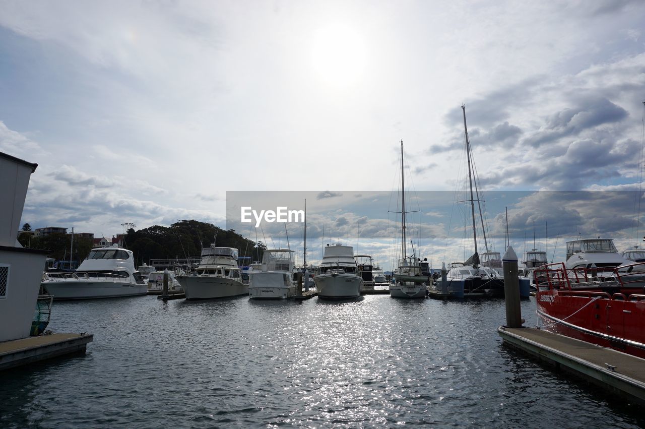 BOATS MOORED AT HARBOR AGAINST SKY