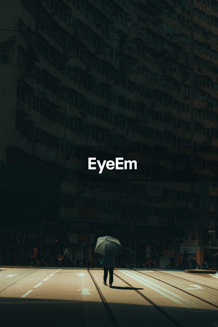 Woman walking on street amidst buildings in city