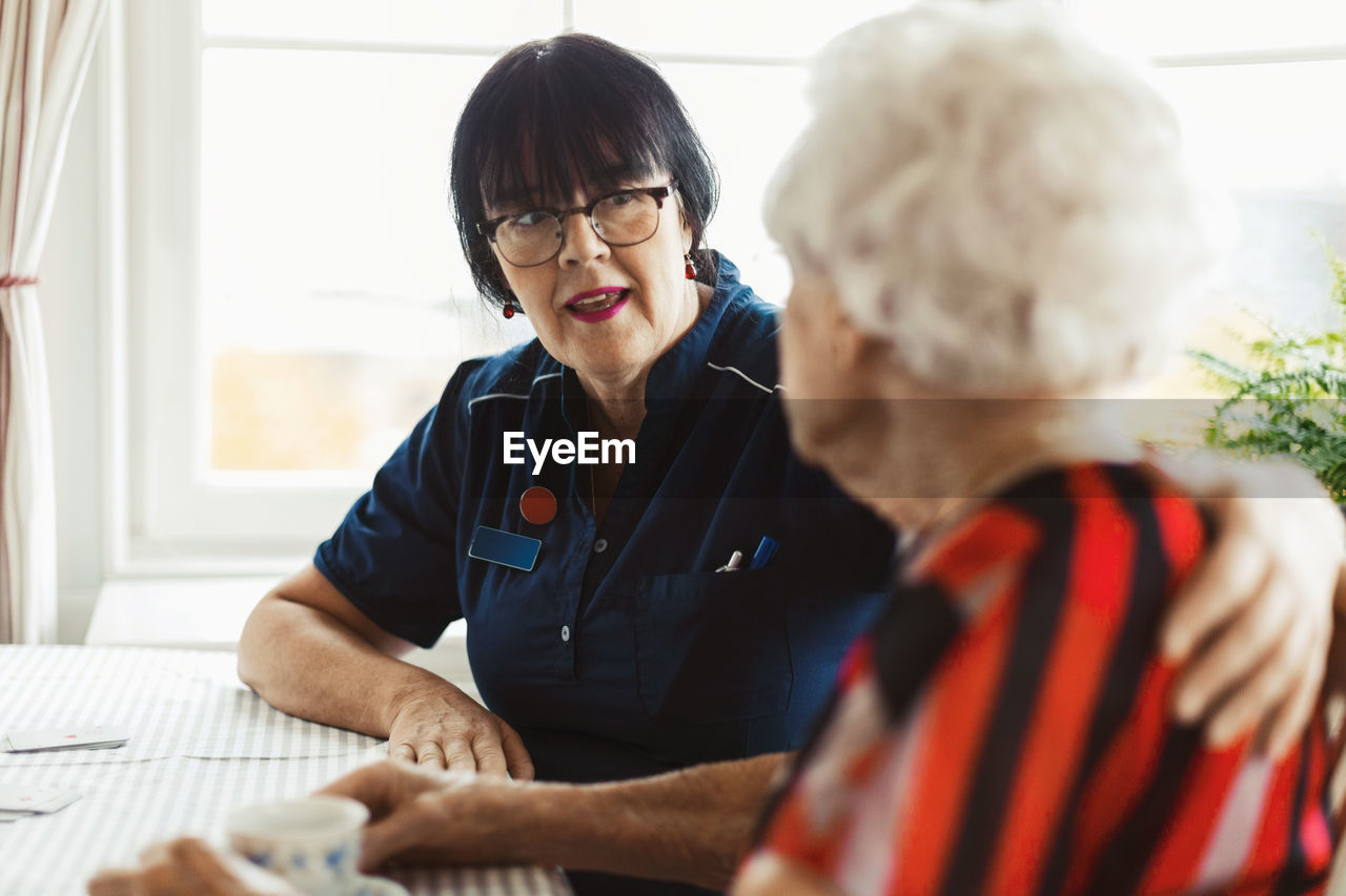 Caretaker talking to senior woman at home