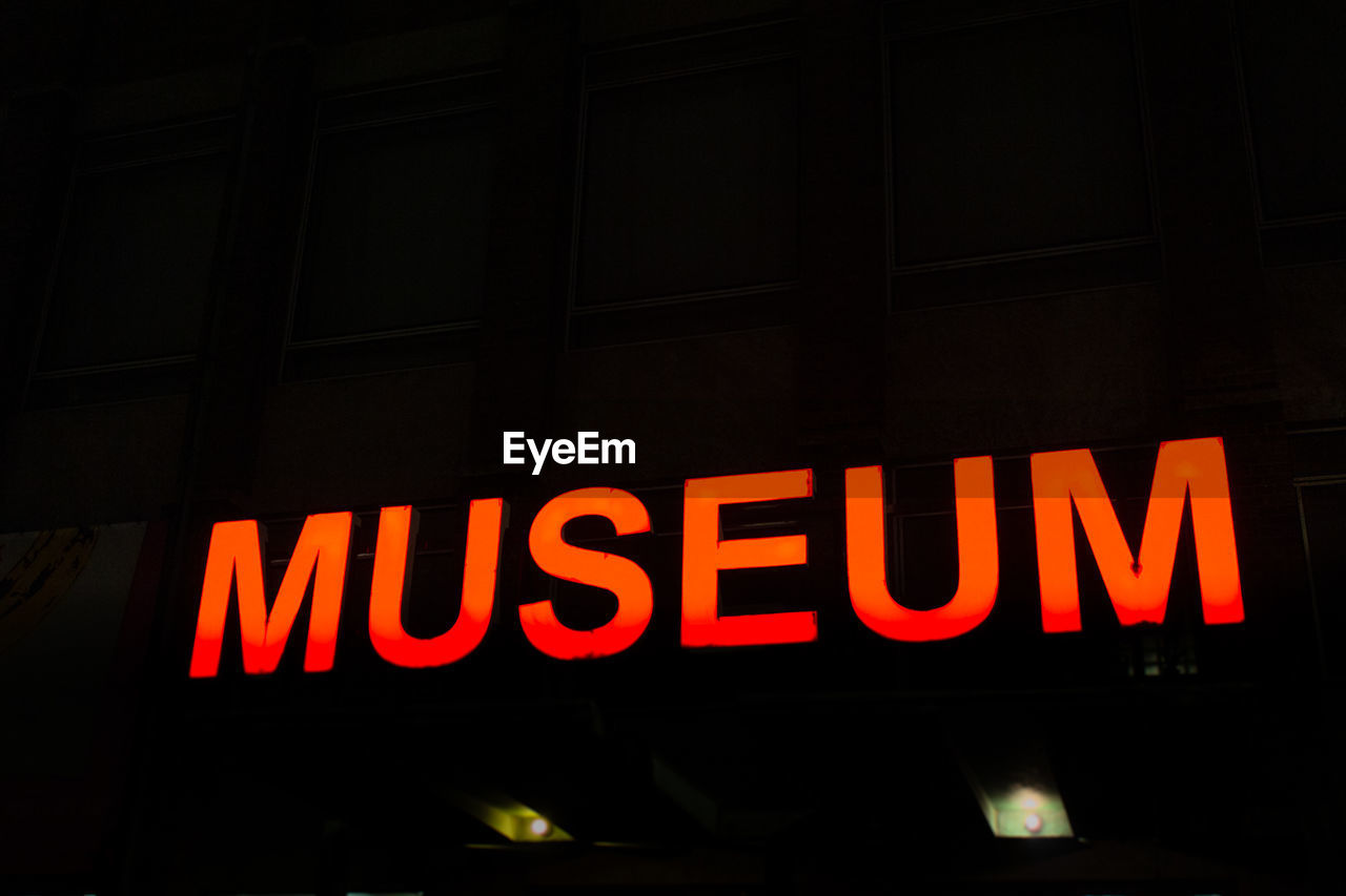 LOW ANGLE VIEW OF ILLUMINATED INFORMATION SIGN IN CITY