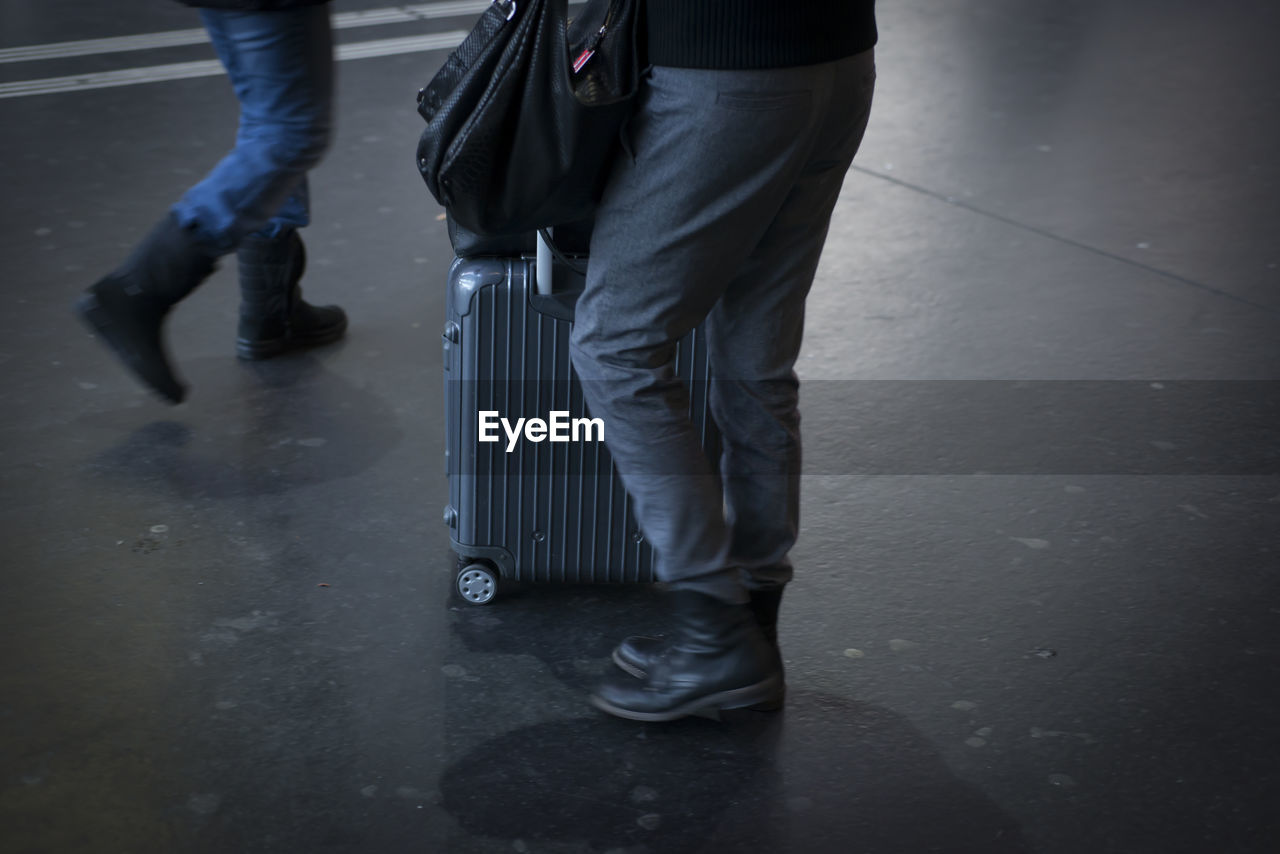 Low section of man with luggage standing on floor