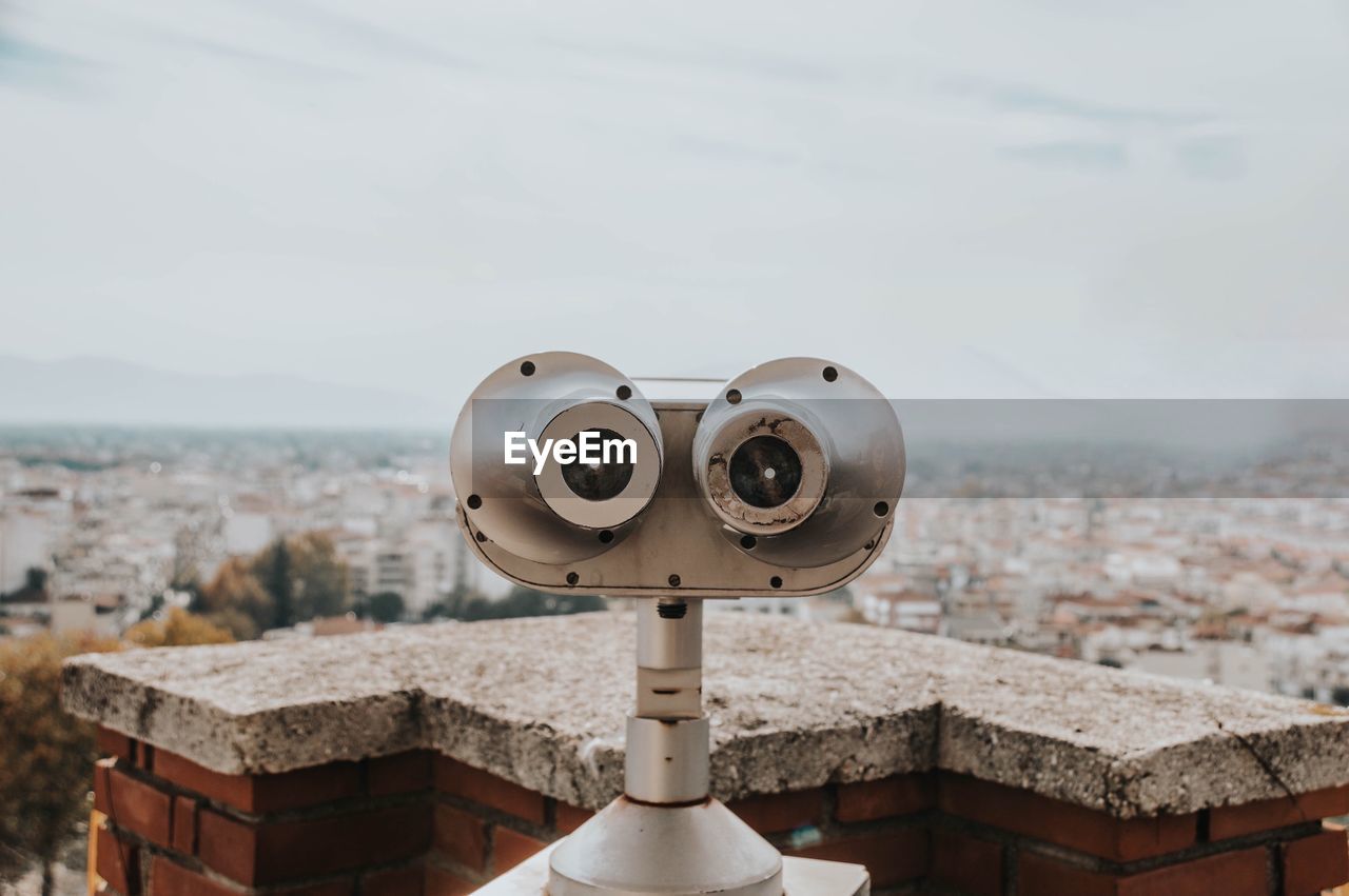 Close-up of coin-operated binoculars against buildings in city