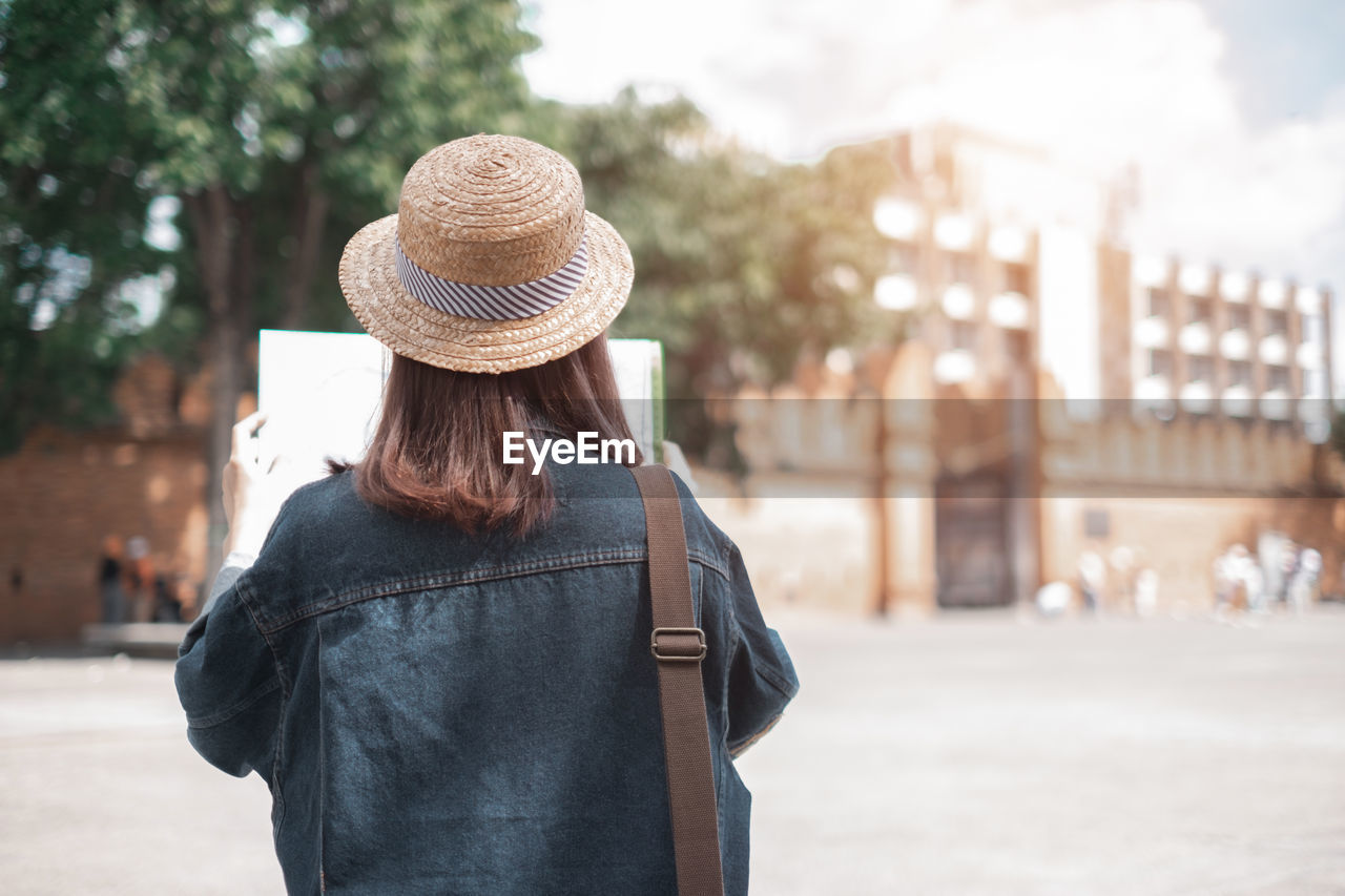 REAR VIEW OF WOMAN STANDING BY STREET