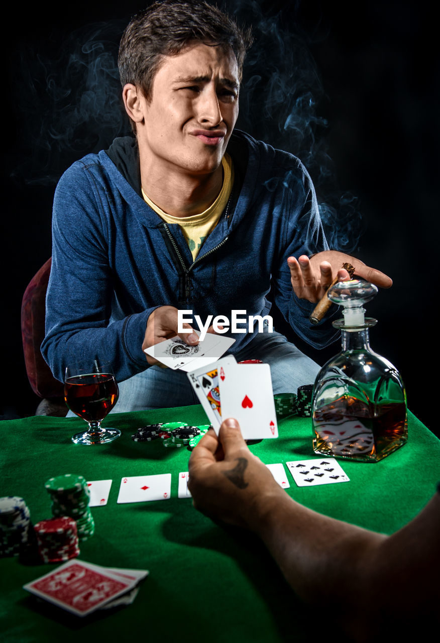 Men playing poker against black background