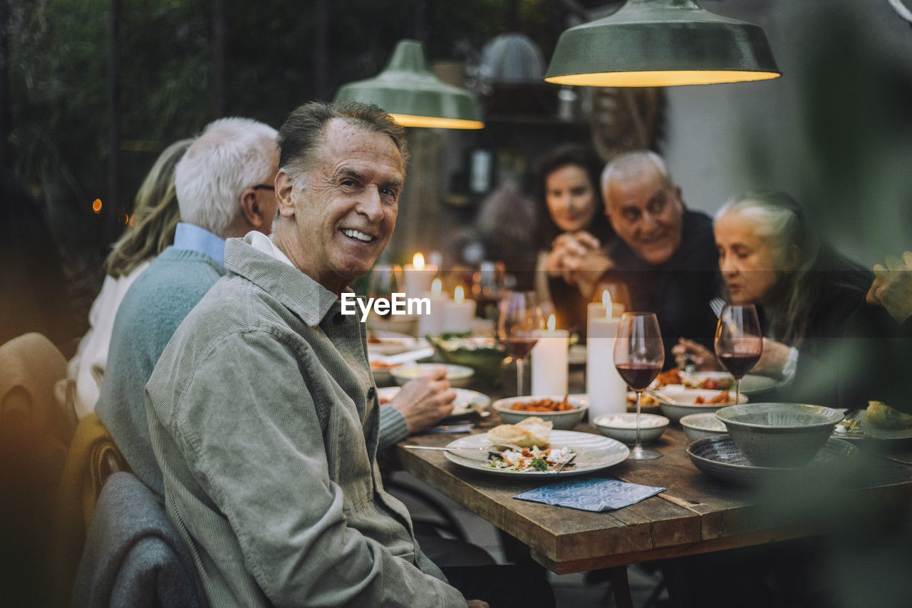 Portrait of happy senior man with friends during dinner party