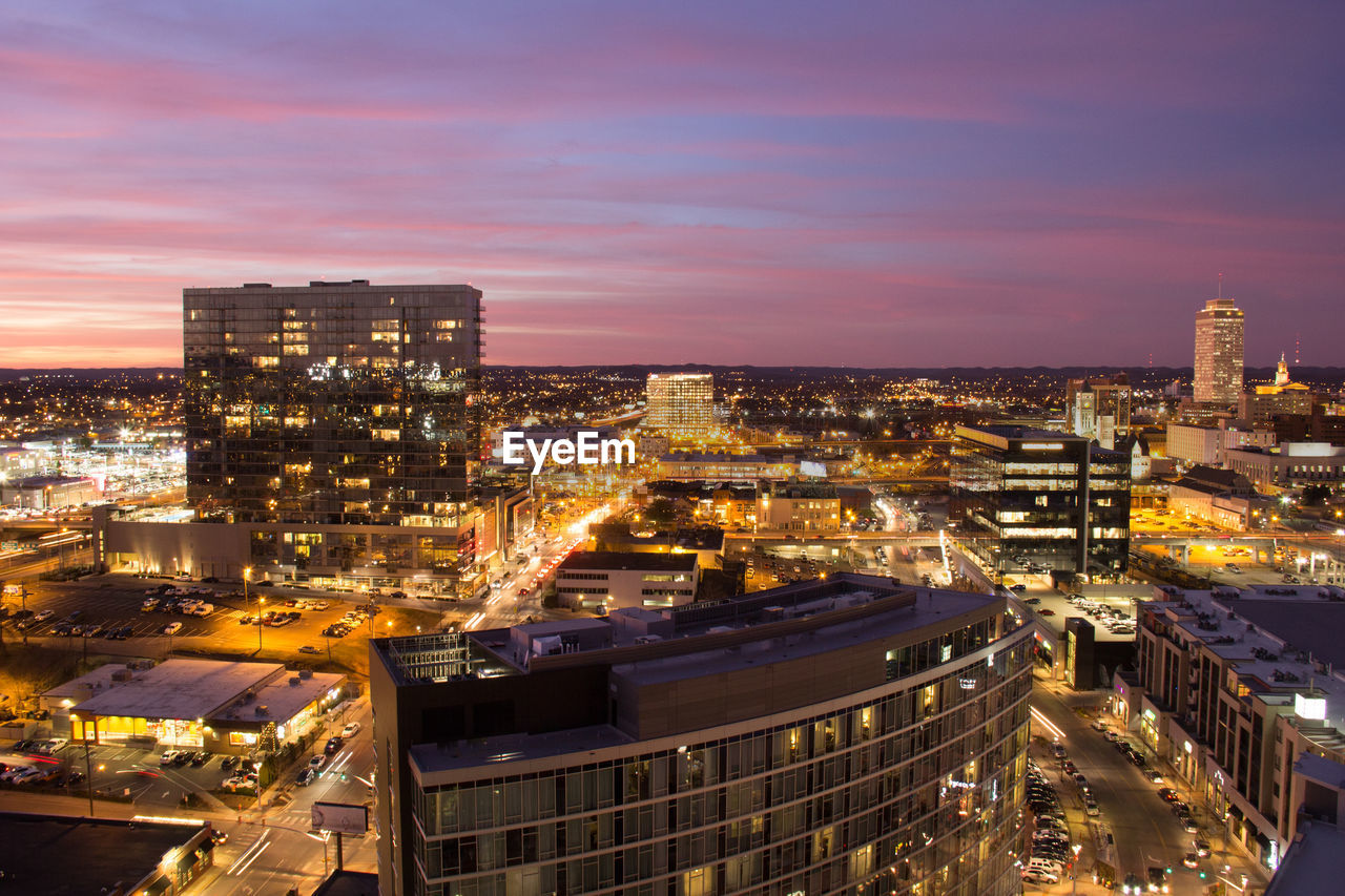 Illuminated cityscape against sky at dusk