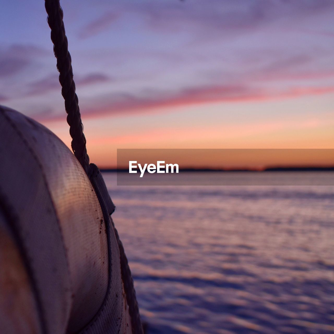 CLOSE-UP OF BOAT MOORED ON SEA AGAINST SKY DURING SUNSET