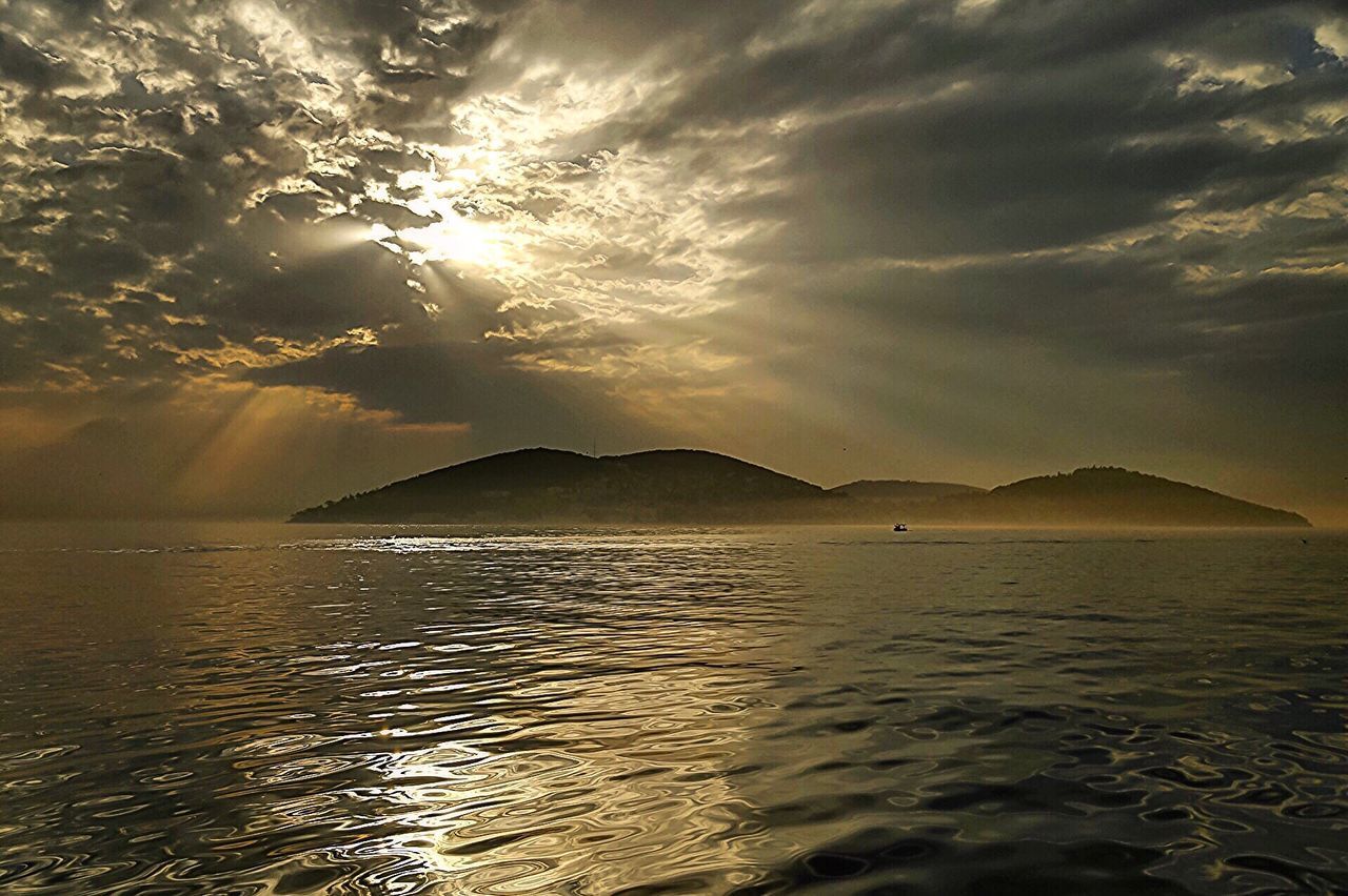 Scenic view of lake and mountains against cloudy sky during sunset