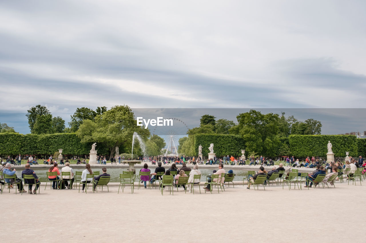 People amidst fountain against sky