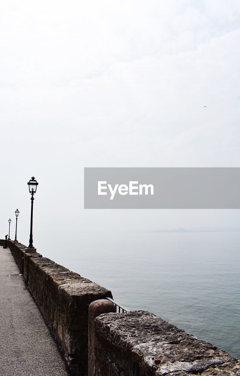 STREET LIGHTS BY SEA AGAINST SKY