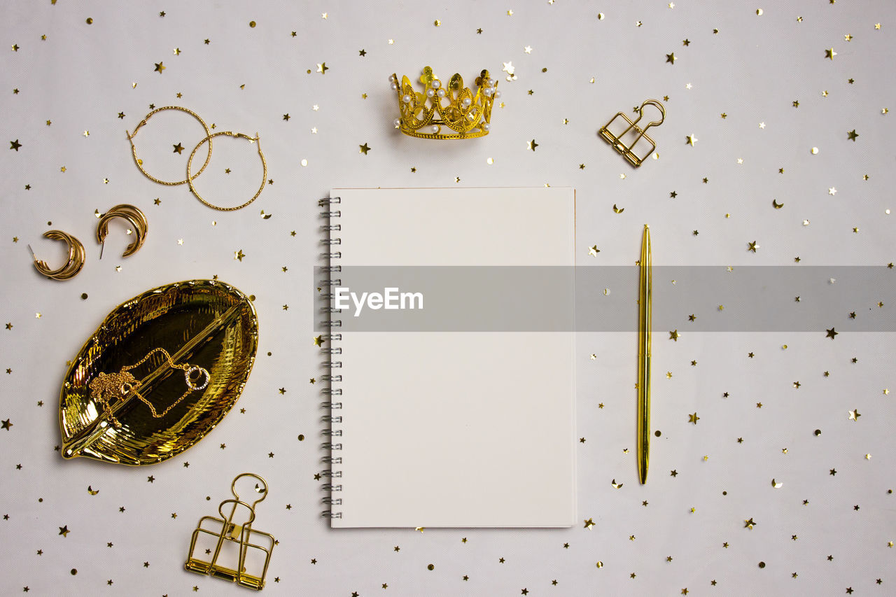 A notebook with golden items over the golden background.